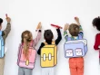 Camarades d'école prêts à écrire sur un mur, vus de dos