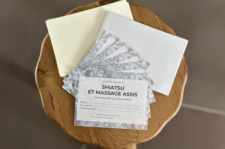 Cartes cadeau pour un shiatsu ou un massage Amma assis, posées sur un tabouret
